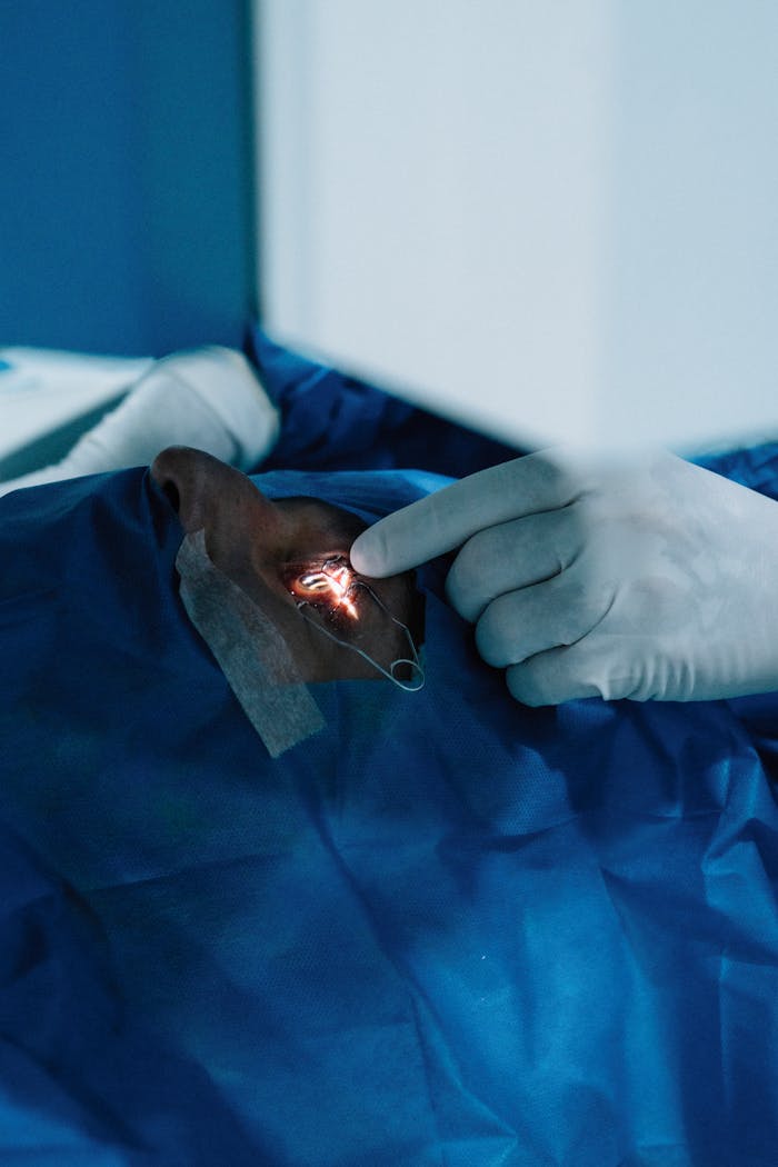 A precise eye surgery operation showing a surgeon's hand and surgical instrument under bright lighting.