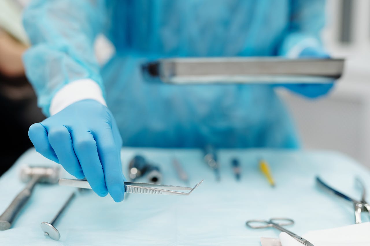 Blue-gloved hand handles surgical tools in a medical setting, focusing on precision and cleanliness.